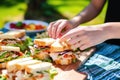 hand selecting chicken club sandwich from a picnic spread