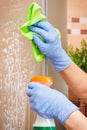 Hand of senior woman cleaning glass shower in bathroom using microfiber cloth and detergent Royalty Free Stock Photo