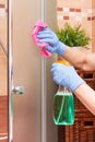 Hand of senior woman cleaning glass shower using microfiber cloth and detergent, household duties concept Royalty Free Stock Photo