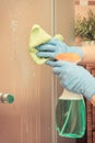 Hand of senior woman cleaning shower using green microfiber cloth and detergent, household duties concept Royalty Free Stock Photo