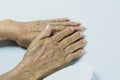 Hand of senior woman with lotion bottle on white table Royalty Free Stock Photo