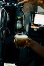 Hand serving beer in glass using tap. Bartender pouring beer while standing at bar counter.  Barman hand at beer tap pouring an Royalty Free Stock Photo