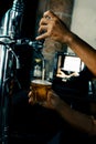 Hand serving beer in glass using tap. Bartender pouring beer while standing at bar counter.  Barman hand at beer tap pouring an Royalty Free Stock Photo