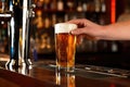 hand serving chilled pint of lager at a home bar