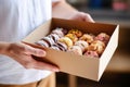 hand serving a donut from a bakery box