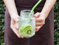 Hand on serving glass of iced kiwi soda drink