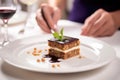 hand serving a piece of moussaka onto a white plate