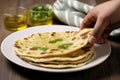 hand serving a piece of peshwari naan on a white plate