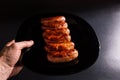 Hand serving sausaged on black background.Serve the table with meat. Roasted sausages on plate Royalty Free Stock Photo