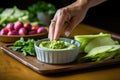 hand setting down a dish of made-from-scratch fava bean dip on a table