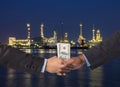 Hand shake between a businessman with dollar money on Petrochemical factory background