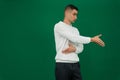 hand shake man a young guy in a white sweatshirt and black jeans on a green chromakey background offers his hand to Royalty Free Stock Photo