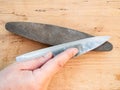 Hand sharpens kitchen knife closeup on whetstone Royalty Free Stock Photo