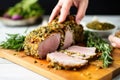 hand showcasing sliced herb crusted pork loin