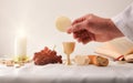 Hand showing a host on the altar with sacred objects