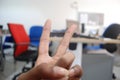 Hand showing peace sign in office