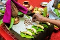 Hand showring rice gains on hindu pooja arrangements containing betel leafs, coconut & x28;pooja kalash& x29;, rice and areca nuts