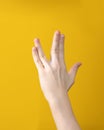 Hand shows Vulcan salute on yellow background. Hand gesture that means Live long and prosper