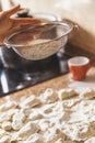 Hand sifts flour through sieve over dough pieces Royalty Free Stock Photo