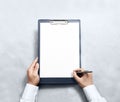 Hand signing blank clipboard with white a4 paper design mockup Royalty Free Stock Photo