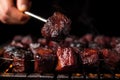 hand skewering grilled burnt ends with a fork
