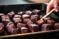 hand skewering stout-marinated beef brisket cubes for grilling