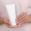 Hand skin care. Female hands holding one white cream tube against body in pink cloth, beautiful beautician woman hands with Royalty Free Stock Photo