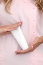 Hand skin care. Female hands holding one white cream tube against body in pink cloth, beautiful beautician woman hands with Royalty Free Stock Photo