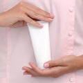 Hand skin care. Female hands holding one white cream tube against body in pink cloth, beautiful beautician woman hands with Royalty Free Stock Photo