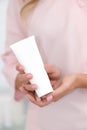 Hand skin care. Female hands holding one white cream tube against body in pink cloth, beautiful beautician woman hands with Royalty Free Stock Photo