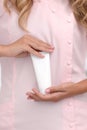 Hand skin care. Female hands holding one white cream tube against body in pink cloth, beautiful beautician woman hands with Royalty Free Stock Photo