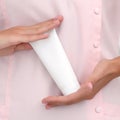 Hand skin care. Female hands holding one white cream tube against body in pink cloth, beautiful beautician woman hands with Royalty Free Stock Photo