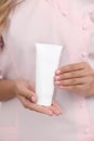 Hand skin care. Female hands holding one white cream tube against body in pink cloth, beautiful beautician woman hands with Royalty Free Stock Photo