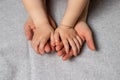 Baby little hands in gentle mother`s parental hands on a gray light background. Royalty Free Stock Photo