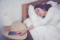 Hand of sleepy woman waking up with alarm clock on mobile phone. Royalty Free Stock Photo