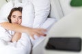 Hand of sleepy woman waking up with alarm clock on mobile phone in bedroom. Alarm morning wake up Royalty Free Stock Photo