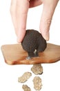 Hand slicing black truffle with wooden truffle slicer