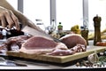 Hand slicing fresh raw pork meat on a cutting board in the kitchen Royalty Free Stock Photo