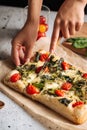 Hand slicing italian bread focaccia with spinach