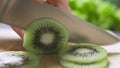 Hand slicing a kiwi with a knife