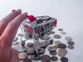 Hand and small shopping cart with various currency coins using as shopping online or marketing concepts