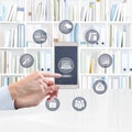 hand with smart phone, finger pointing business icons on screen, isolated on library background, storage and increase of business