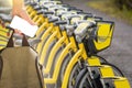 Hand with a smartphone and a backpack in front of a row of rental bikes.