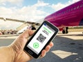 Hand with a smartphone with the digital green pass of the european union and the QR code near plane boarding