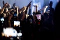 Hand with a smartphone records live music festival, Taking photo of concert stage. Party at nightclub with crowd of people raising