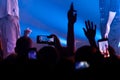 Hand with a smartphone records live music festival, Taking photo of concert stage. Party at nightclub with crowd of people raising