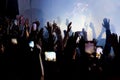 Hand with a smartphone records live music festival, Taking photo of concert stage. Party at nightclub with crowd of people raising