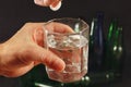 Hand with a soluble tablet from hangover over a glass of water on dark background. Royalty Free Stock Photo