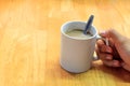 Hand someone holding cup of coffee,spoon and blur wood backgroun