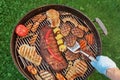 Hand With Spatula And BBQ Grill With Meat And Vegetables